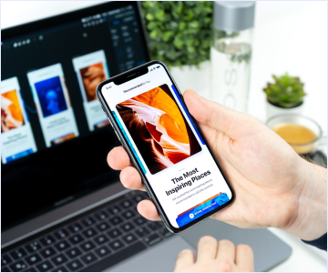smartphone held in hand and computer in the background